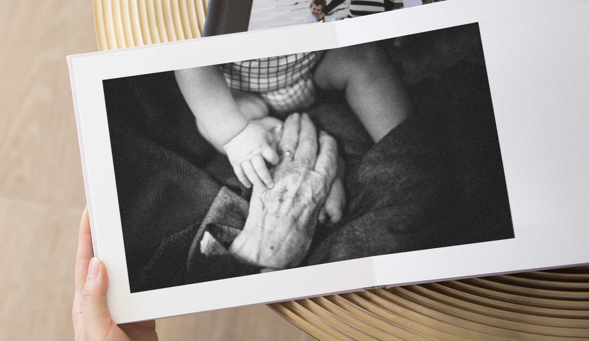 Álbum de fotos abierto con una imagen en blanco y negro de la mano de una persona mayor y la mano de una persona más joven tocándose.