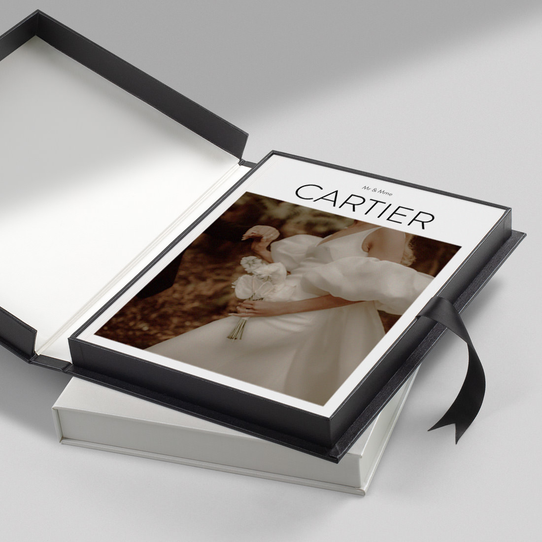 Boîte de présentation pour magazine en bougran noir, ouverte pour présenter le magazine de mariage à l'intérieur.