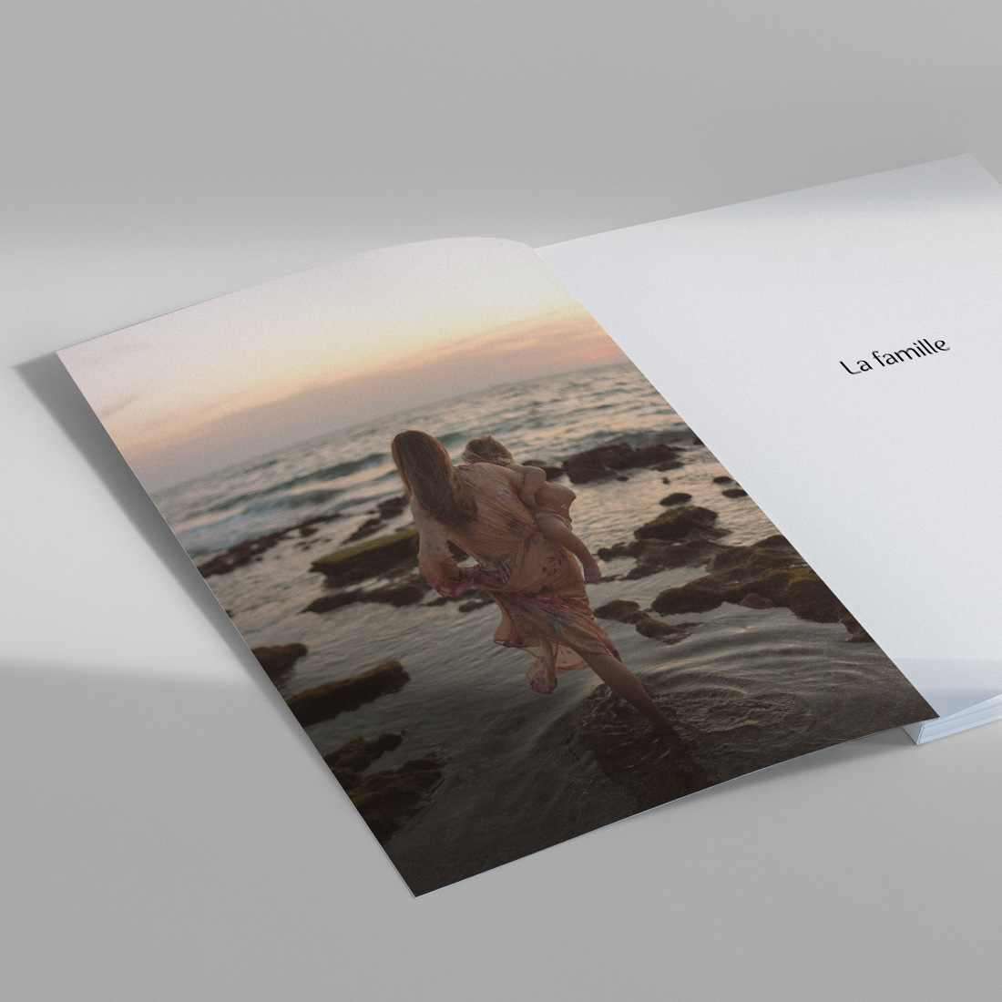 Magazine familial ouvert avec photo d'une mère portant son enfant sur la plage