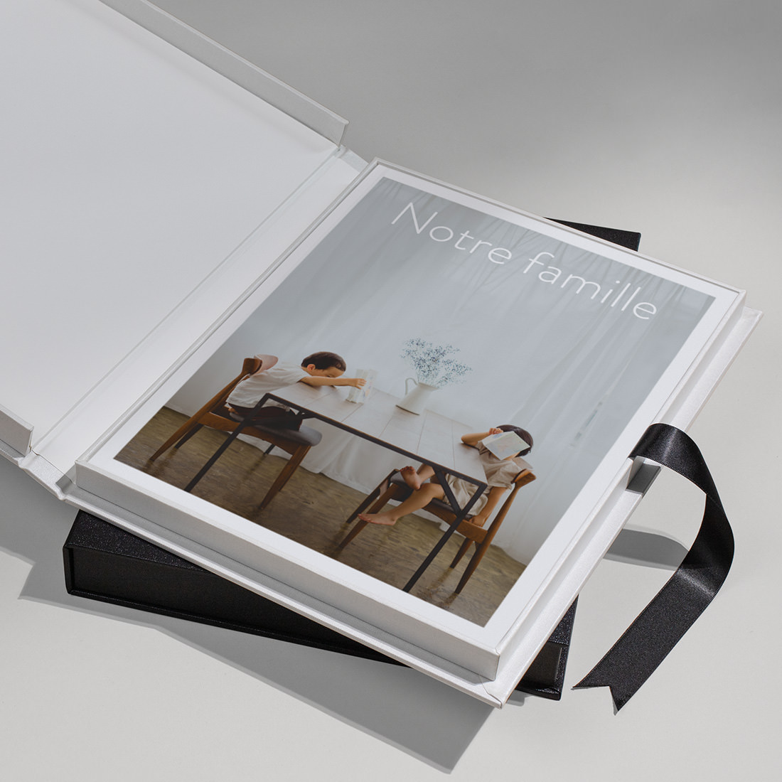 Boîte de présentation de magazines en bougran noir ouverte pour présenter un magazine de la famille empilé.
