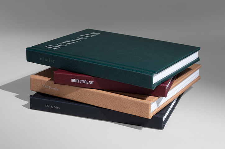 Stack of four premium photo books with new different vegan leather covers