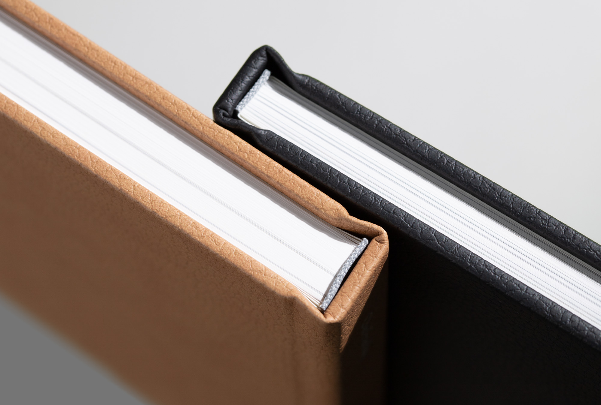 Two premium photo books with vegan leather covers with close up on binding