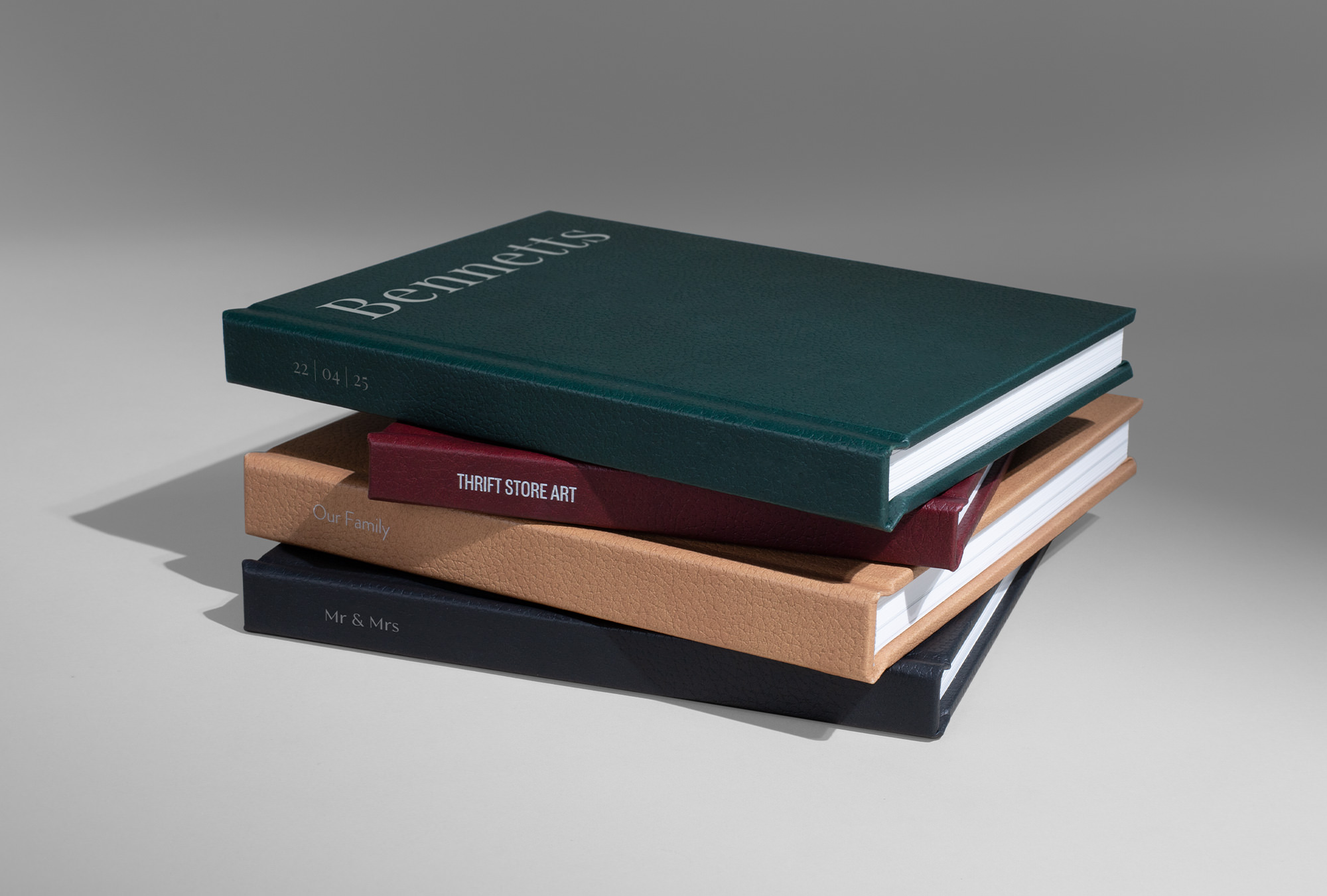 Stack of four premium photo books with new different vegan leather covers