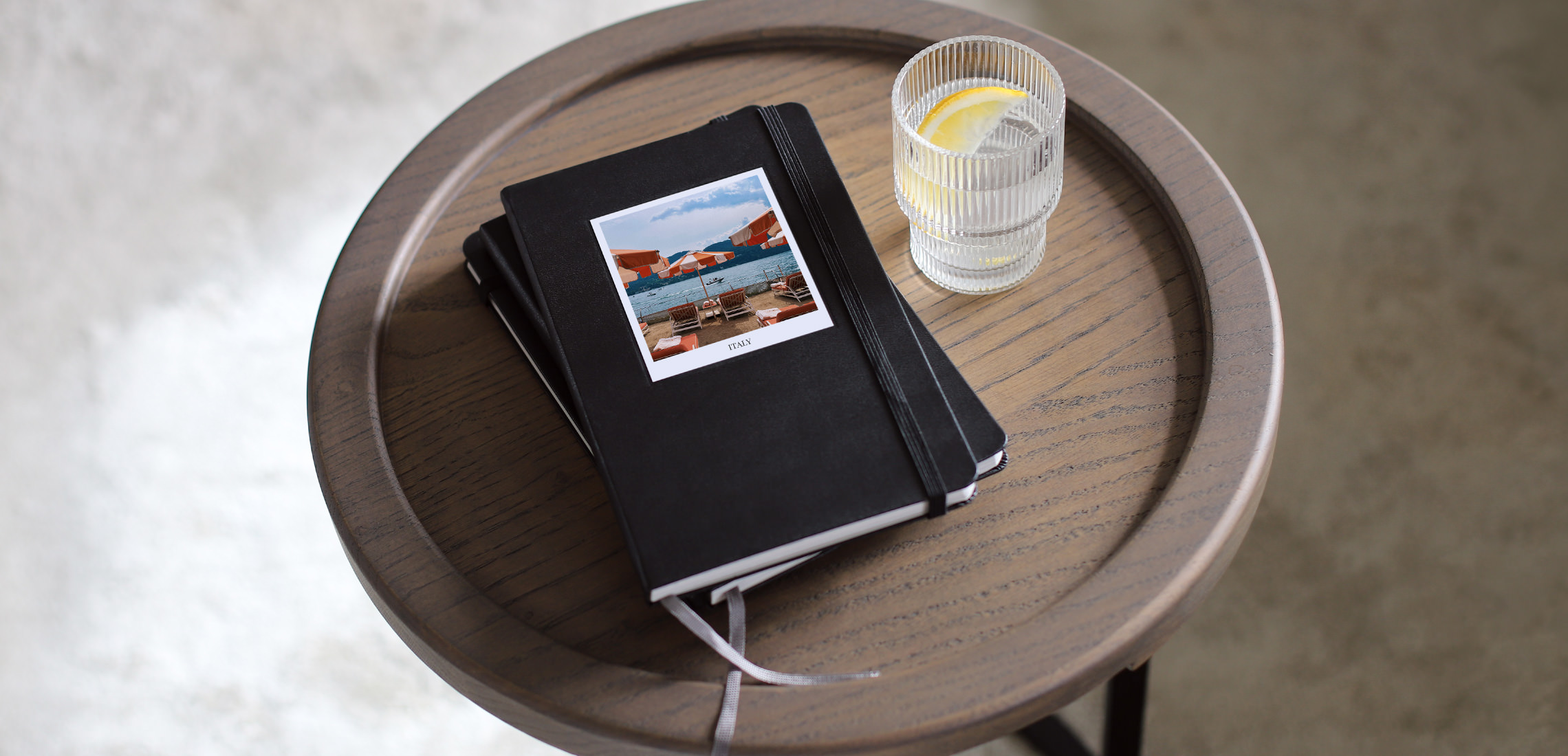 Portrait Moleskine Photo Books stacked on wooden stool table with Italy photo on cover.