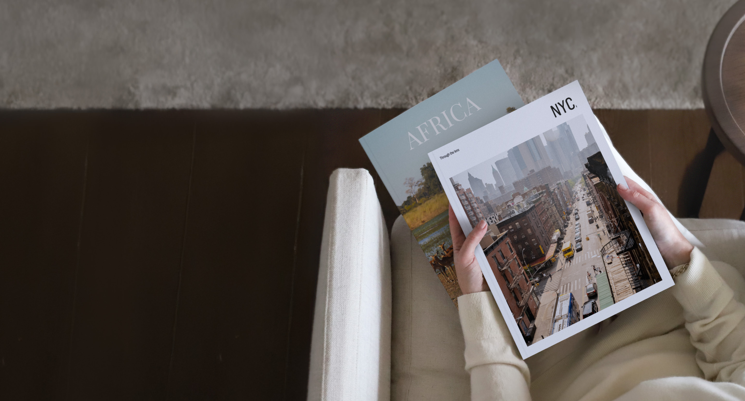 Woman holding two Travel Magazines while seated in beige living room.