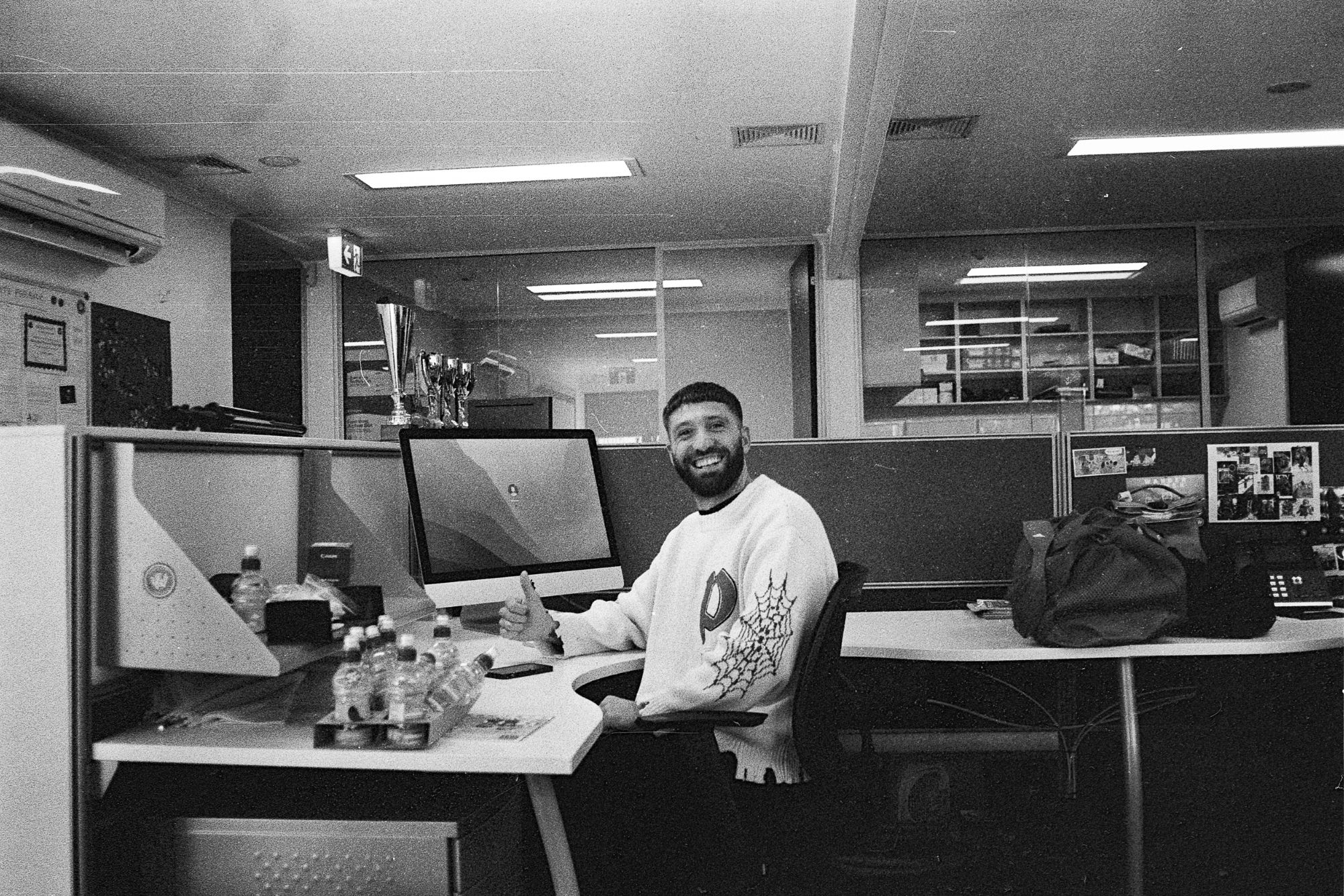 Sitting by desk at job with thumbs up to camera