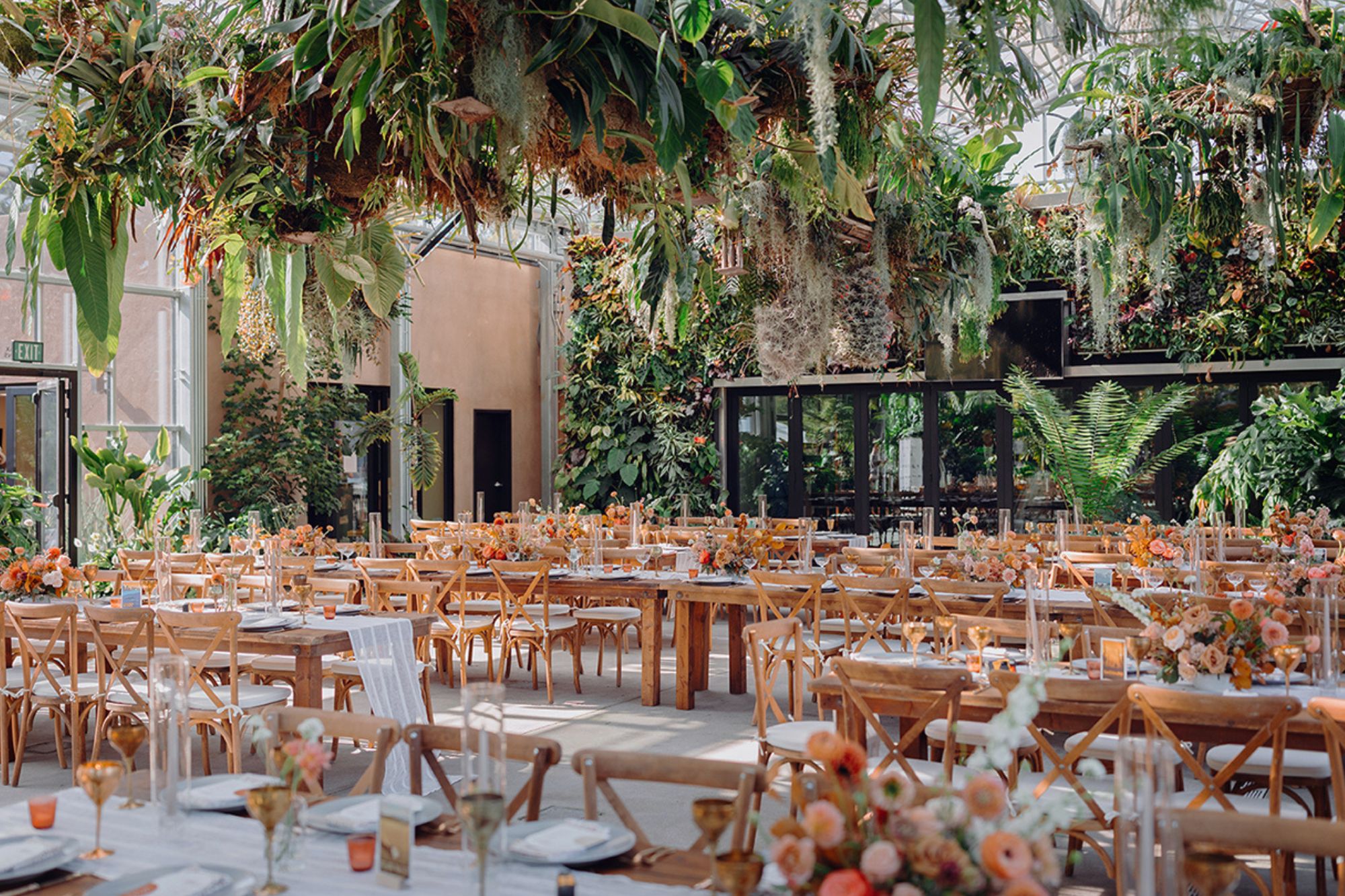 wedding venue with wooden tables and chairs and white linen with lush greenery