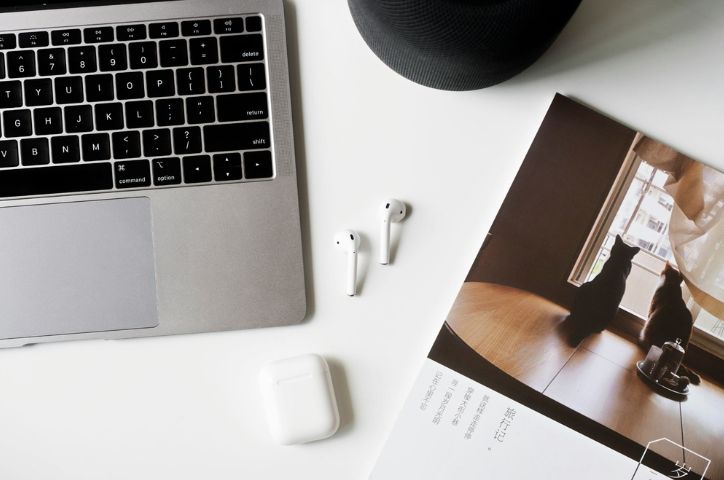 Side of mac keyboard with airpods and book