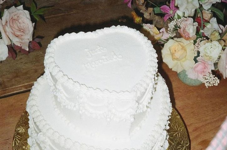 White vintage piped icing cake surrounded by delicate pastel wedding flowers.