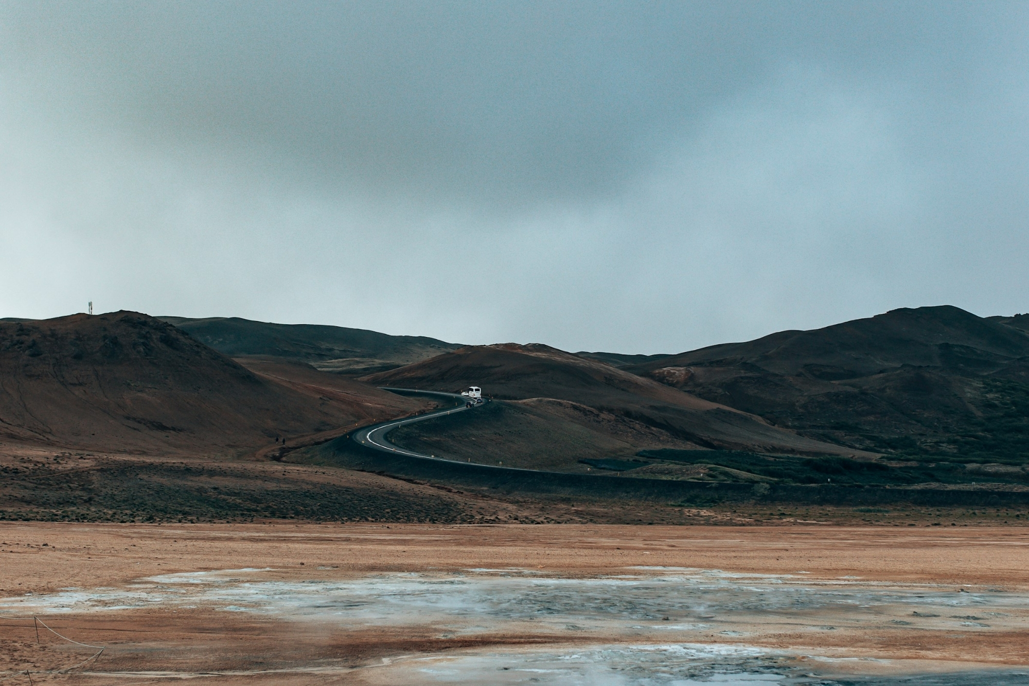 Winding road on volcanic flats in Iceland with overcast skies.