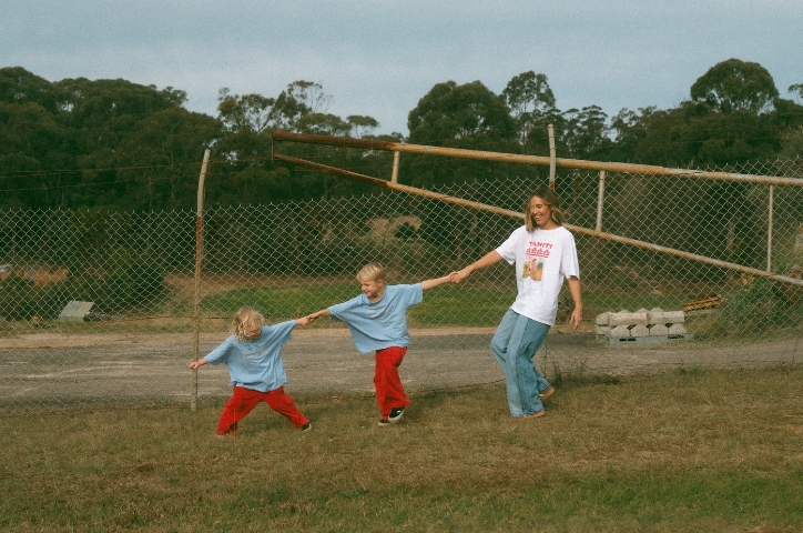 Mother holding hands with her two boy children in a chain formation.