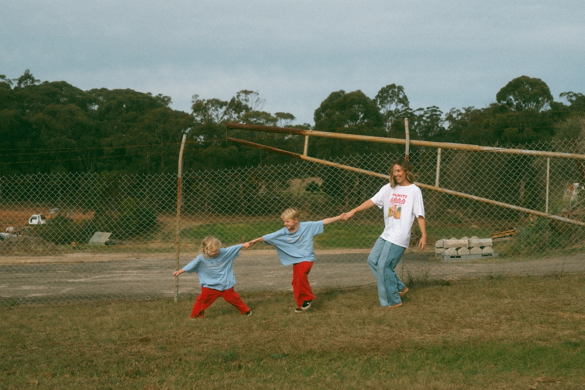 Mother holding hands with her two boy children in a chain formation.
