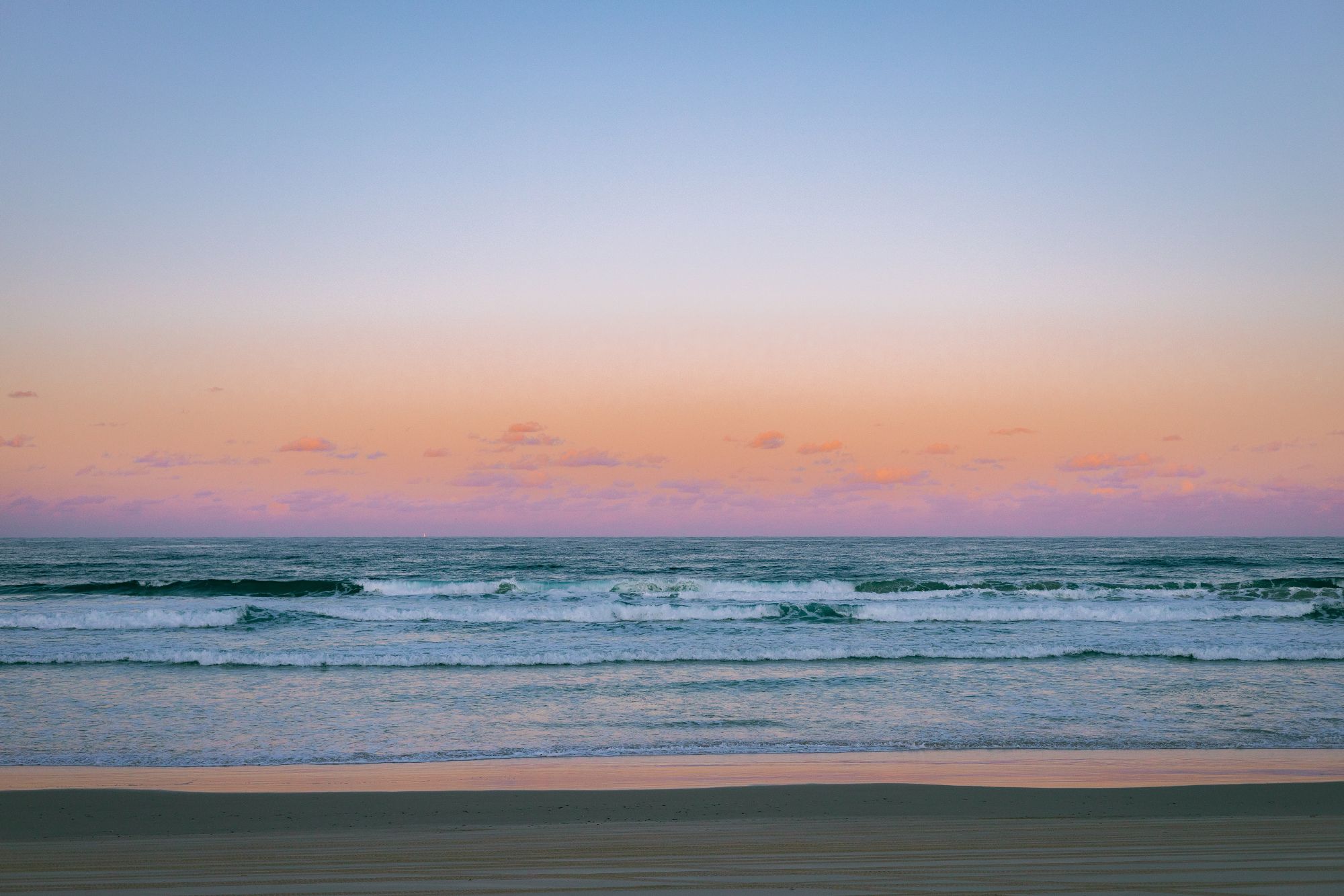 wide shot of beach with pink horizon