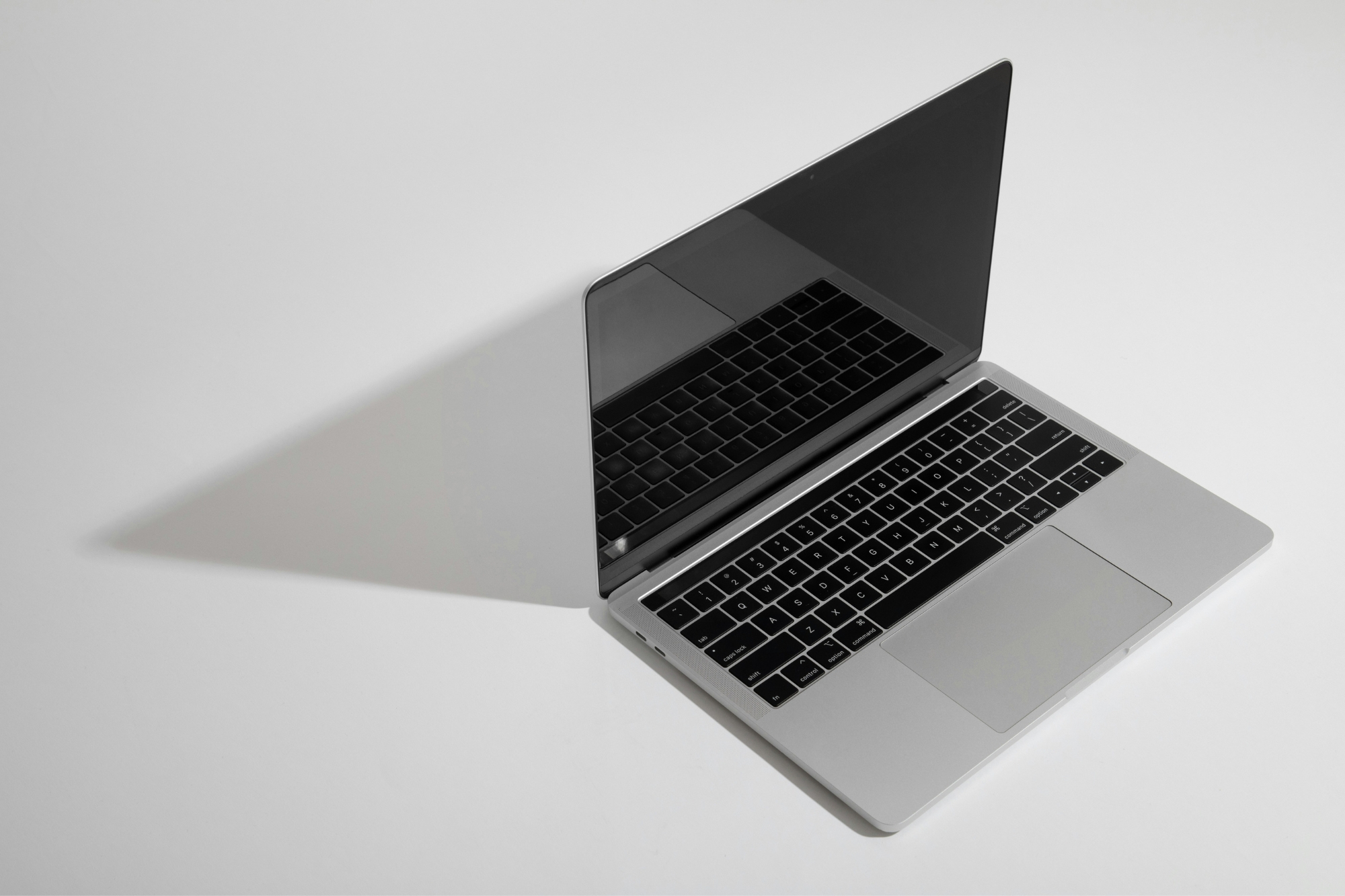 Open Mac laptop on plain grey background.