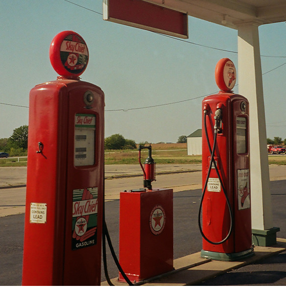 Red gas pumps at station in countryside with warm sunlight casting over.