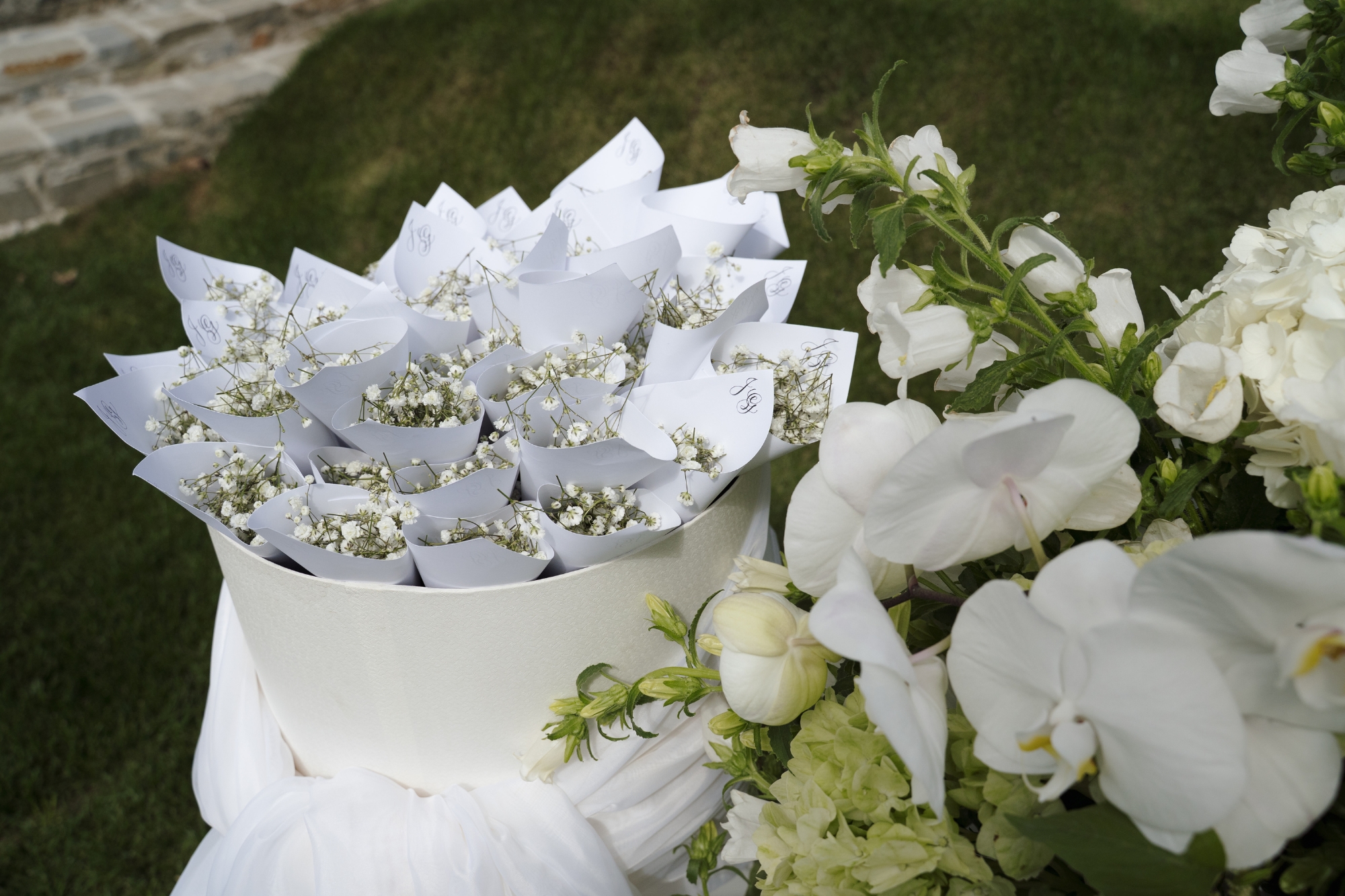 Small bunches of white flowers in paper cups bunched in a white sharing bucket.