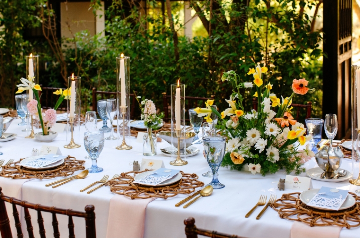 Photo of table setting at wedding with bright yellow and orange flower centerpieces.