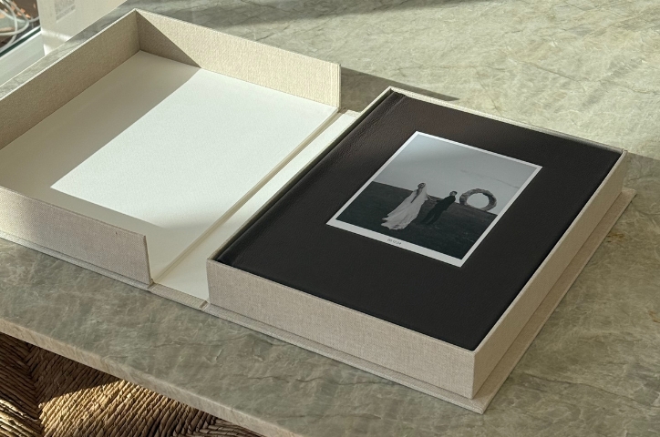 a photo of a wedding photo album in a gift box on a marble table