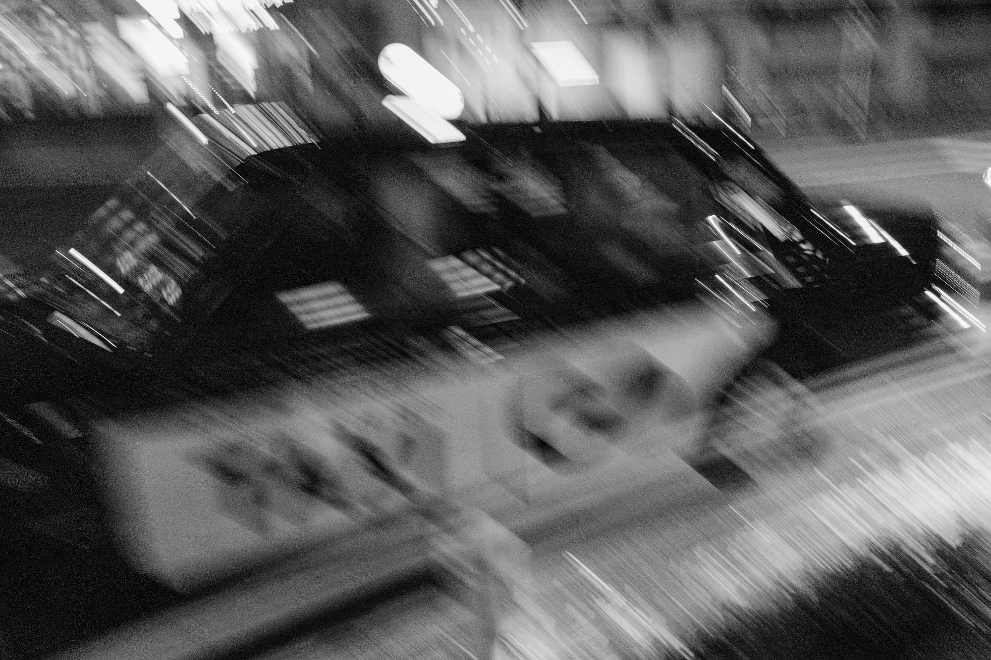 Black and white photo of taxi driving away in blurry moving image.