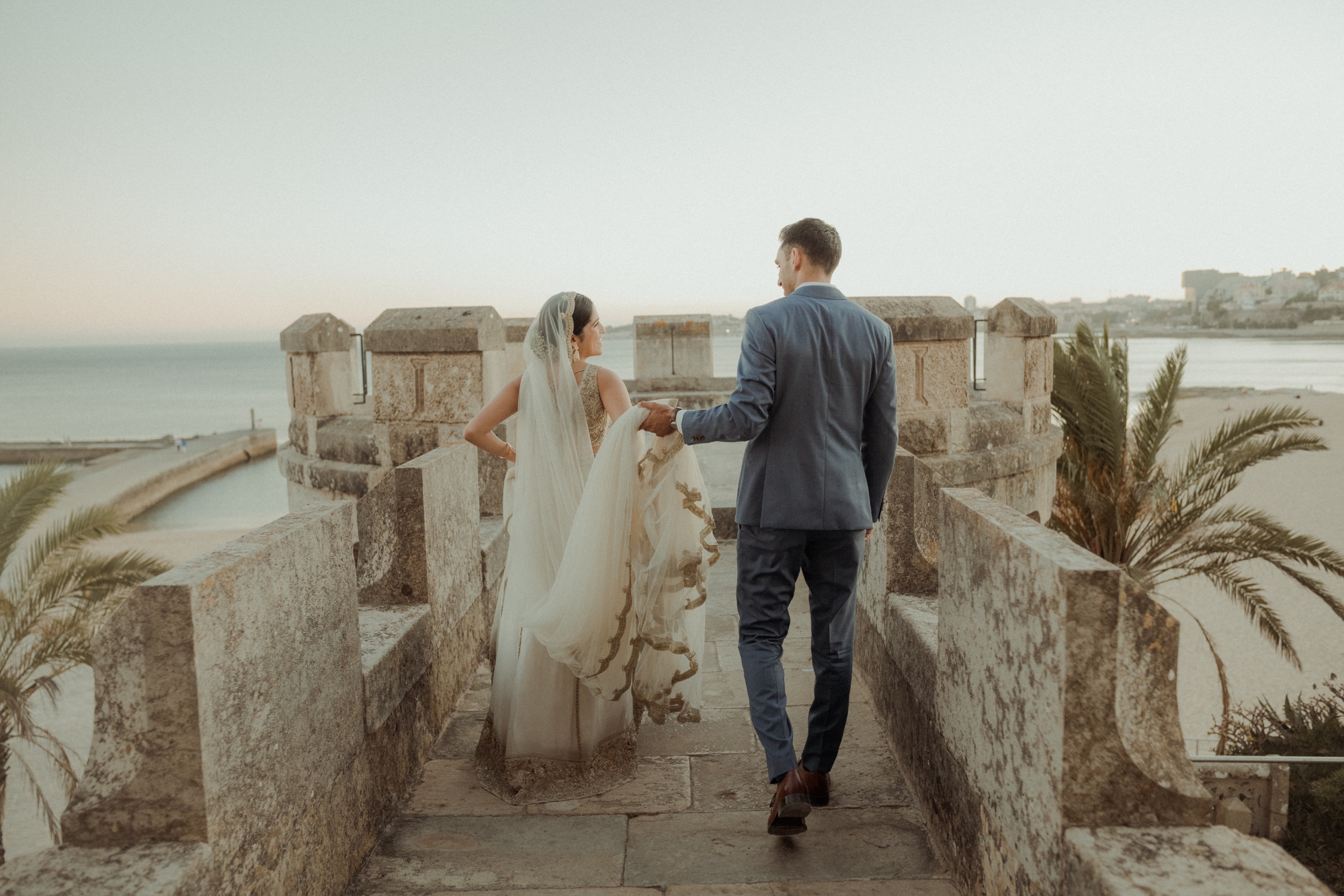 Bride ad groom walking down arch with groom holding vail