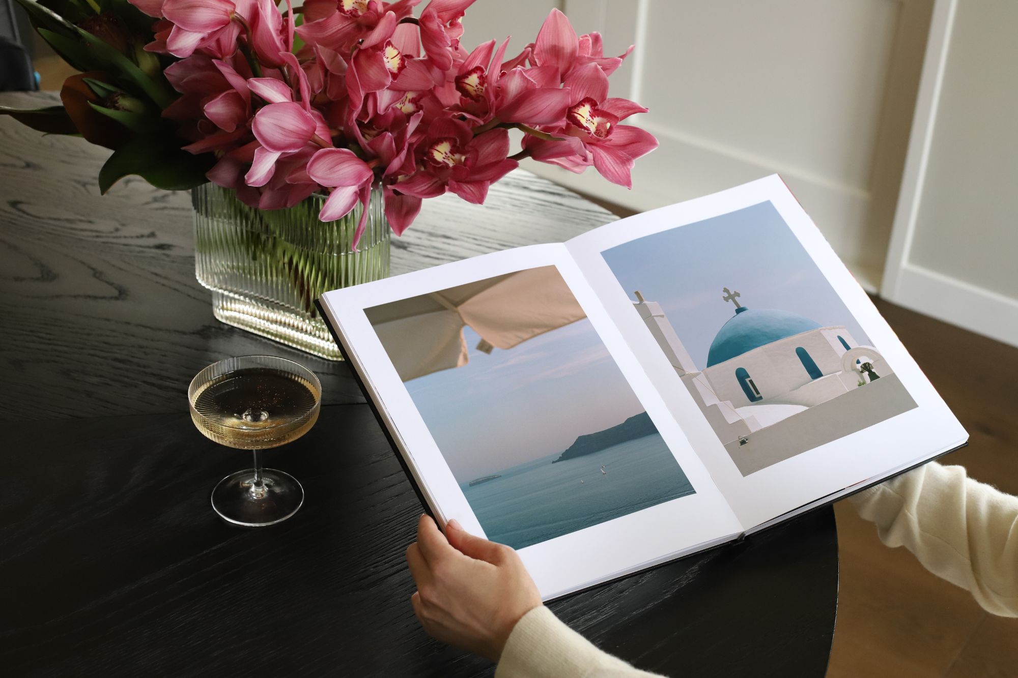 Hands opening a Portrait Premium Photo Album with photos of Greece on double page spread.