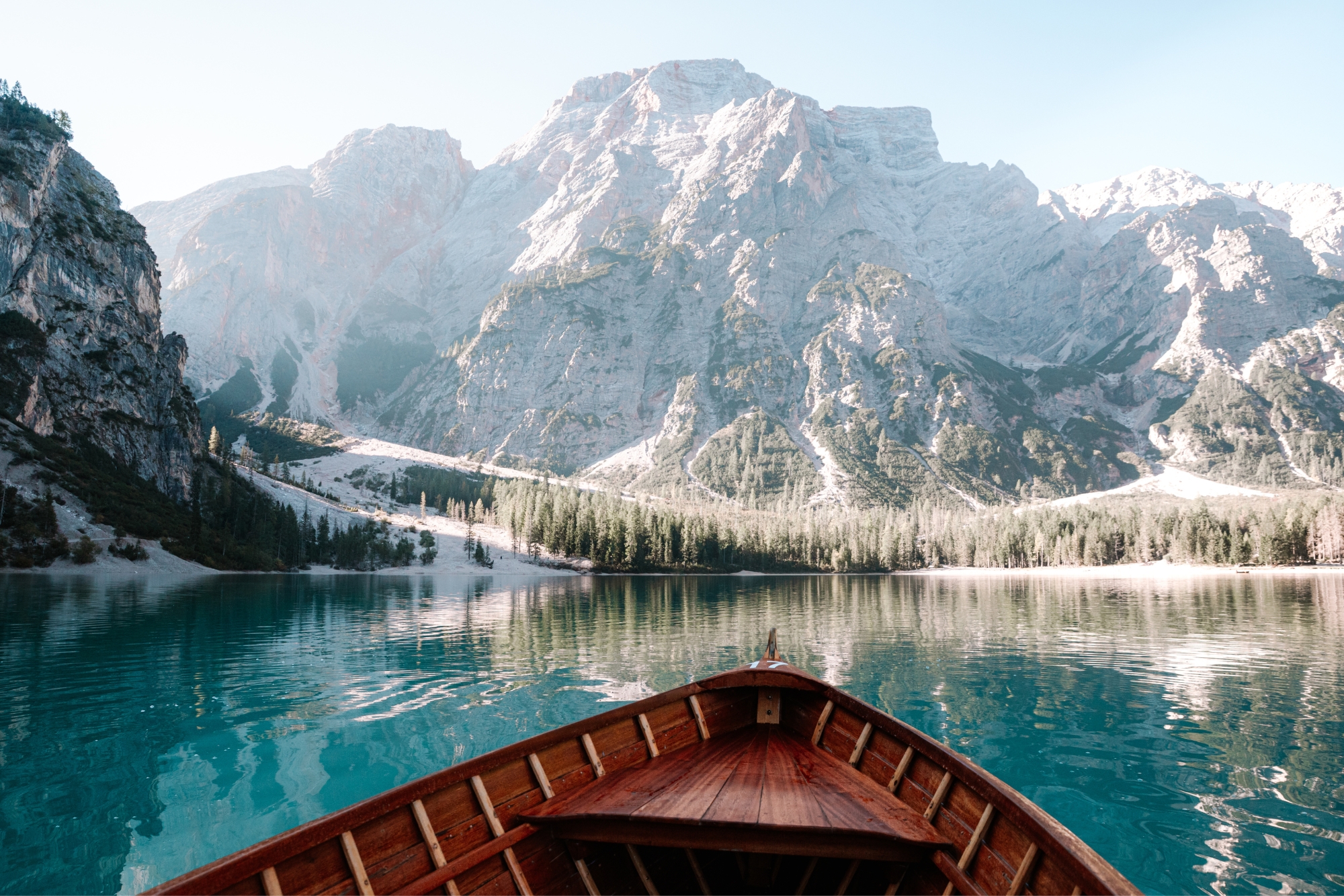 Wooden boat on lake surrounded by tall snowy mountains