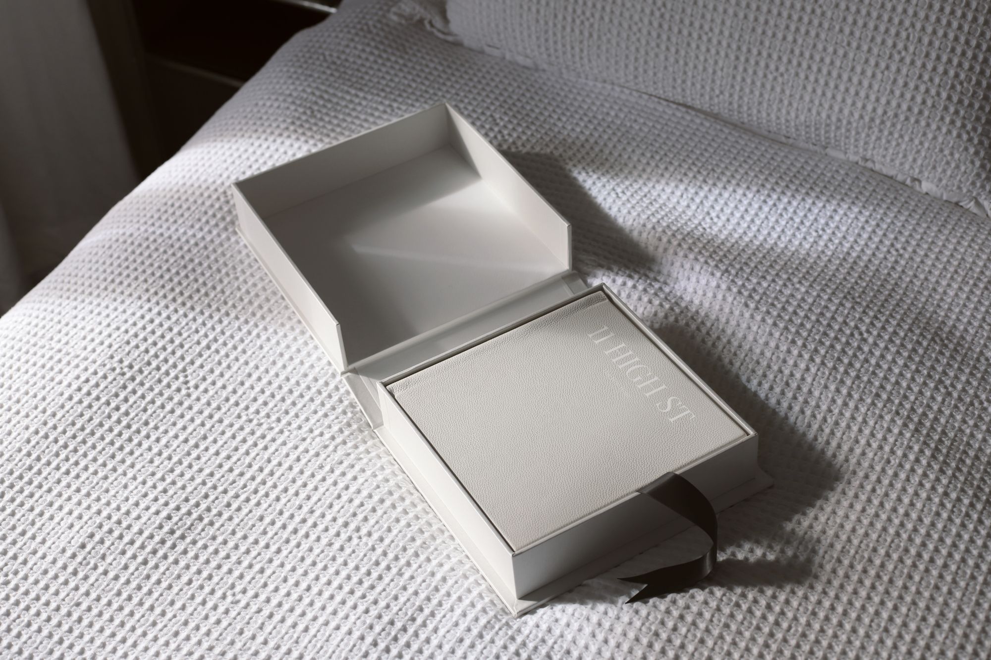 photo of leather photo album and gift box on white bedspread