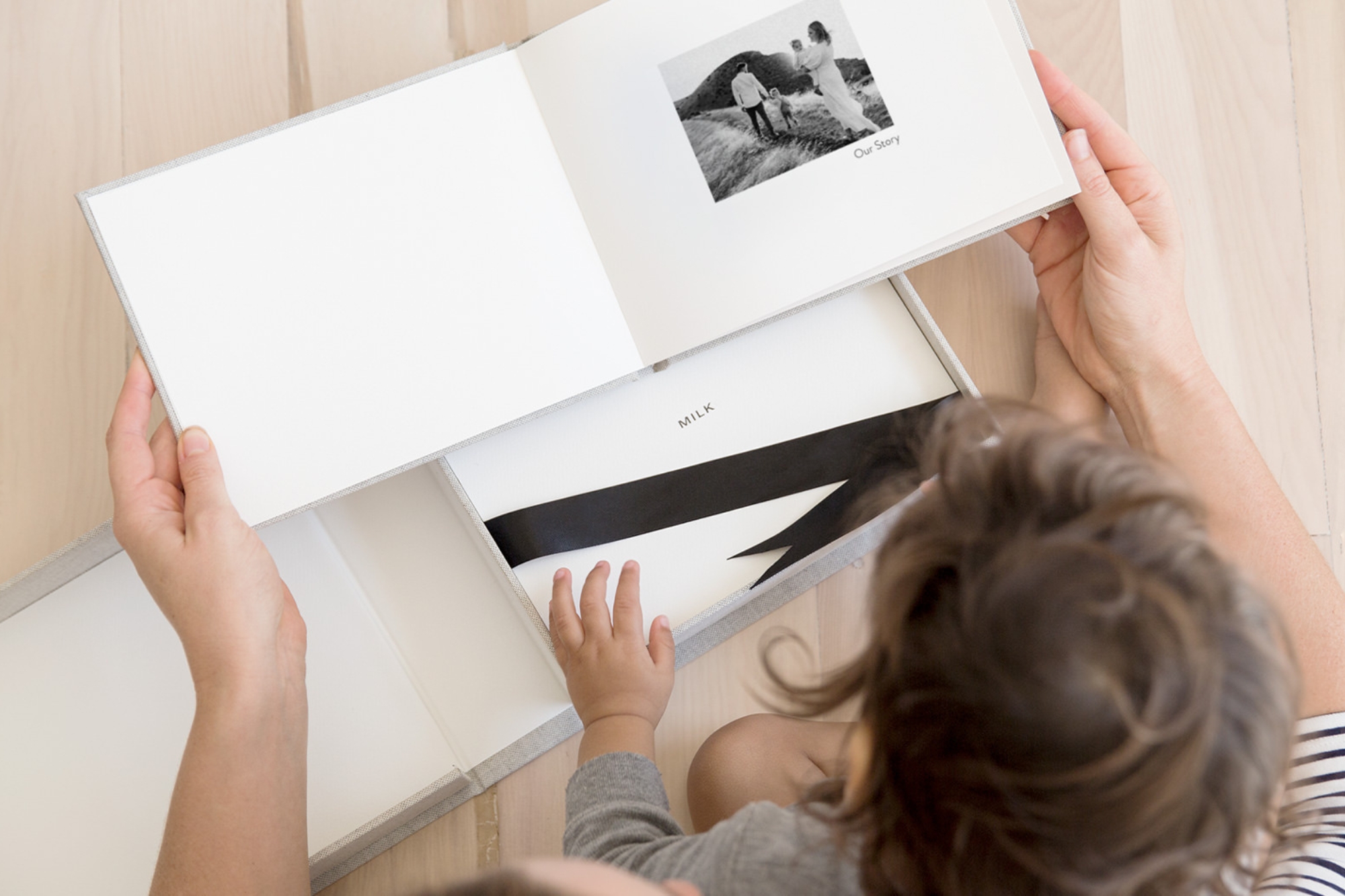Father and son flip through a Medium Landscape Premium Photo Book with an additional Presentation Box to fit, with the MILK logo on inside.