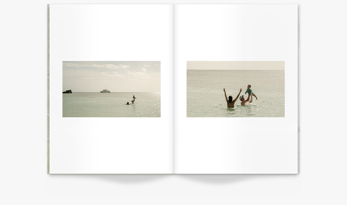 Travel Magazine featuring a couple lifting a toddler while swimming in ocean under late midday sunshine.
