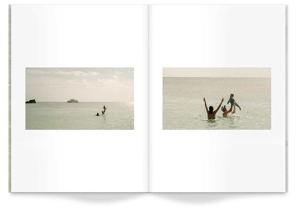Travel Magazine featuring a couple lifting a toddler while swimming in ocean under late midday sunshine.