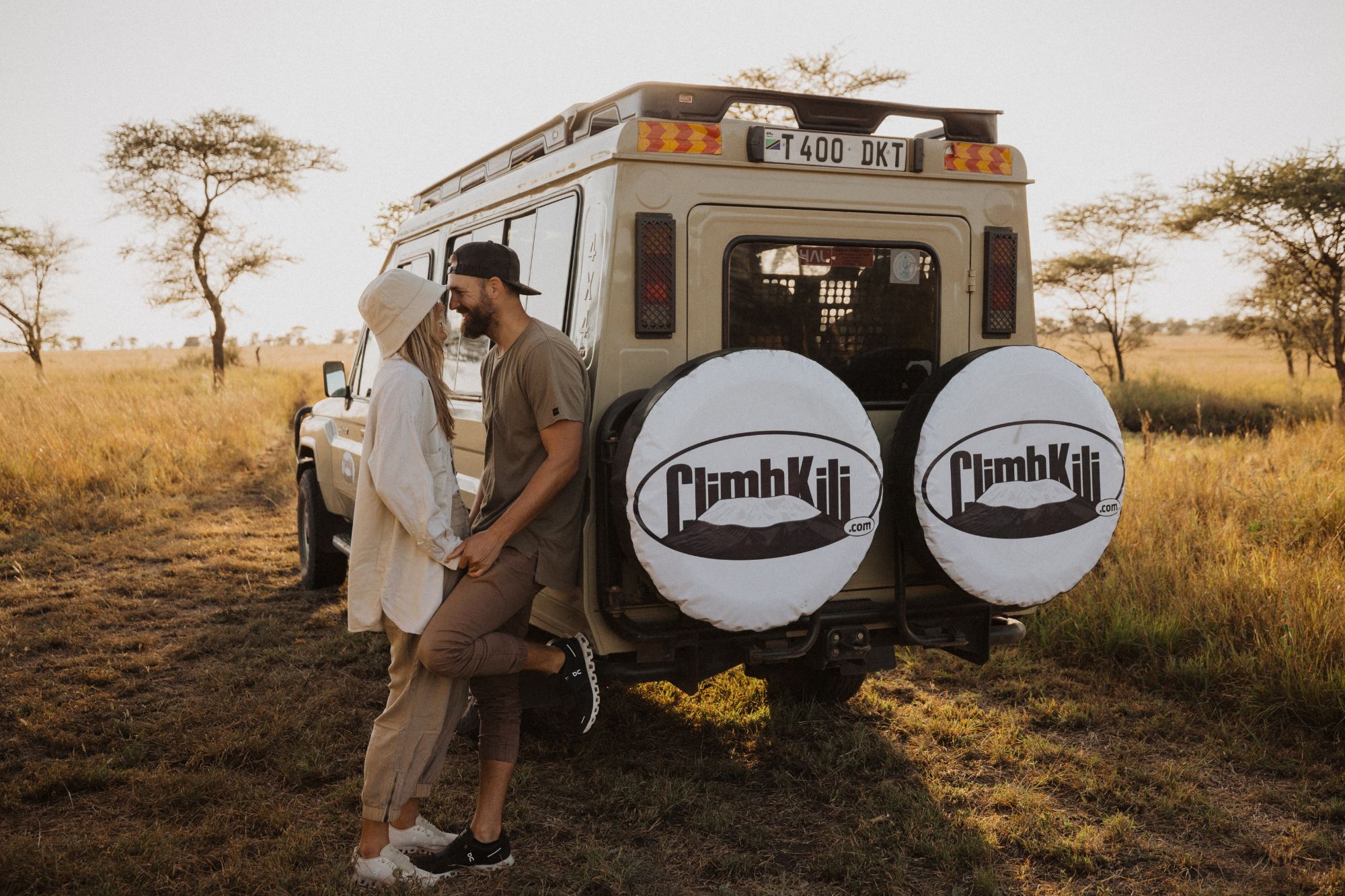 A couple smiling and leaning against a car