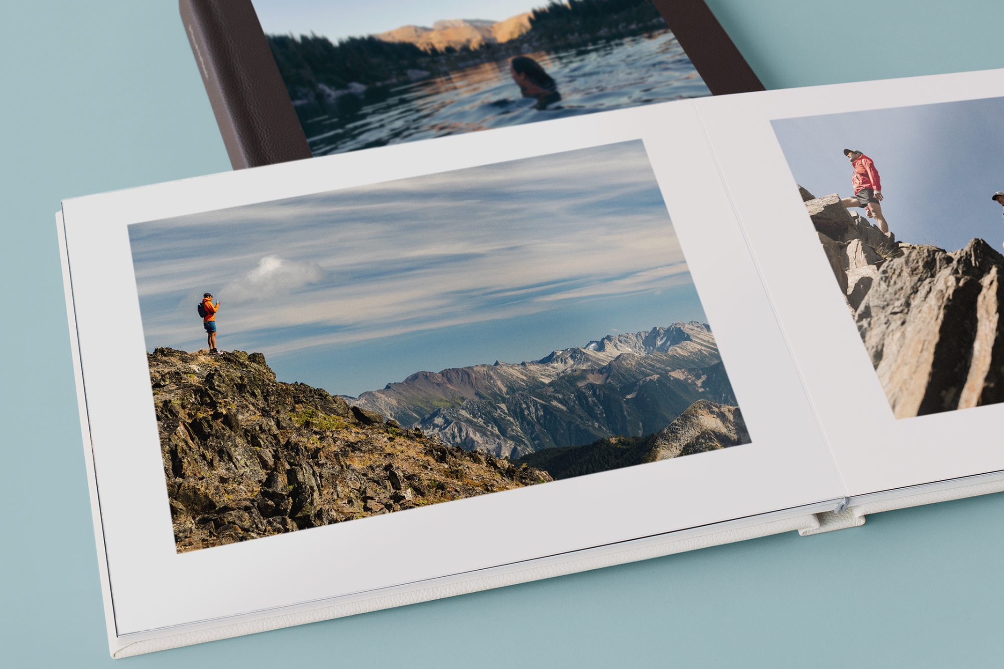 Travel photo book open revealing photos of cliff overlooking mountains.