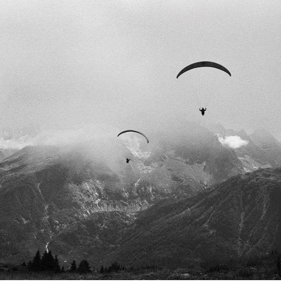 Parachuters flying across mountain range in Europe.
