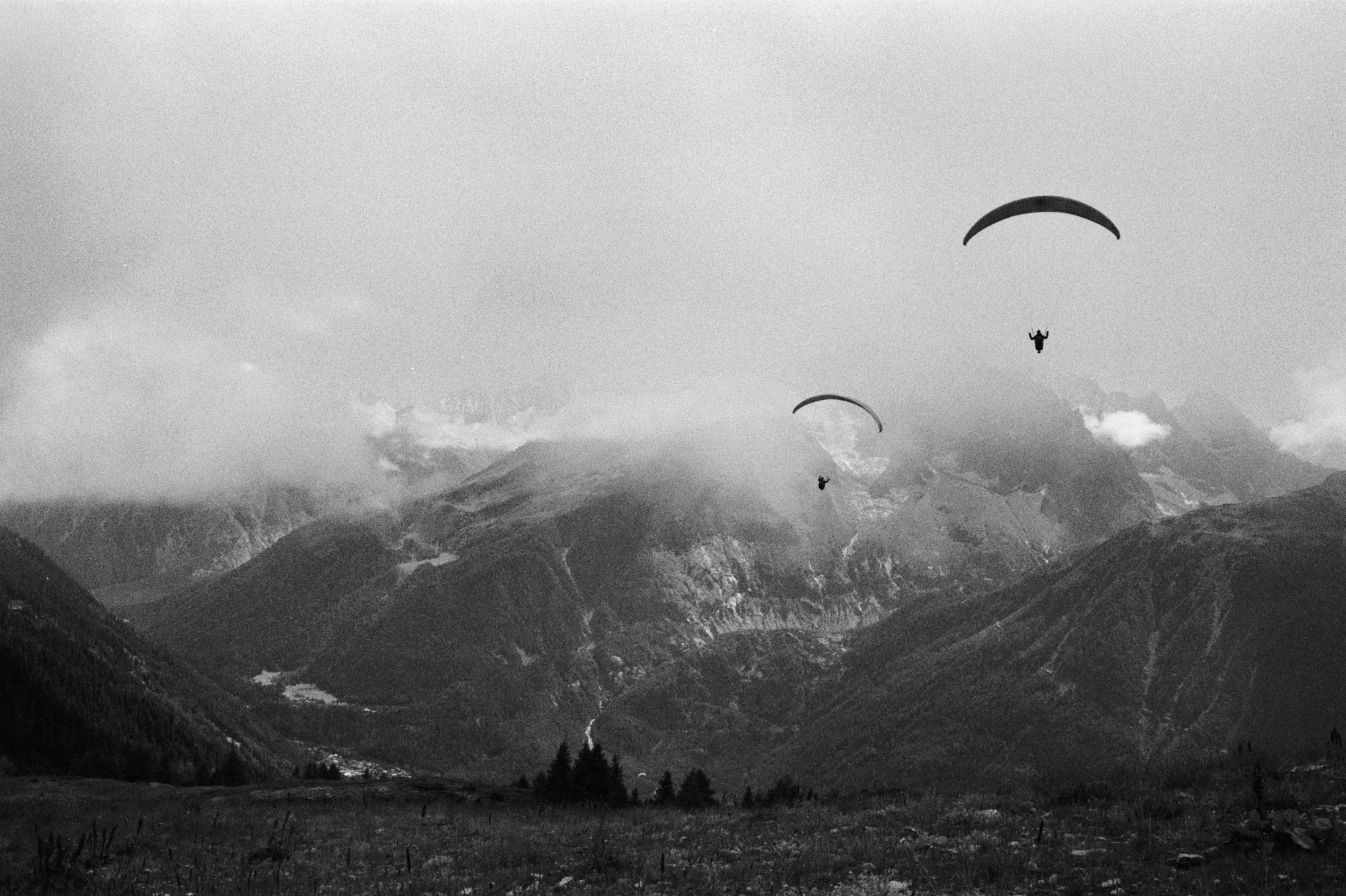 Paragliders flying through mountains cape in France.