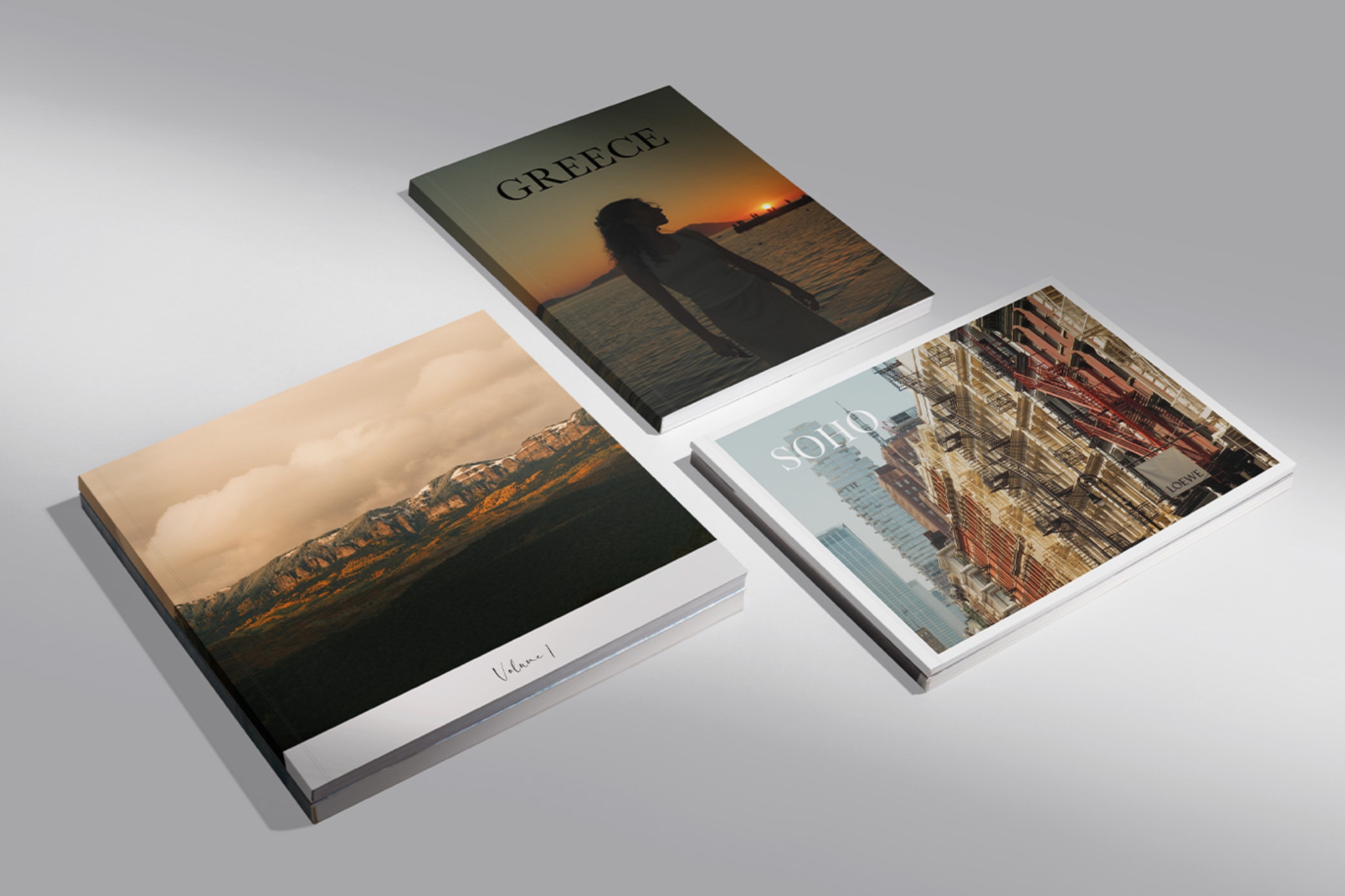 Three Softcover Photo Books in different orientations laid on a grey background.