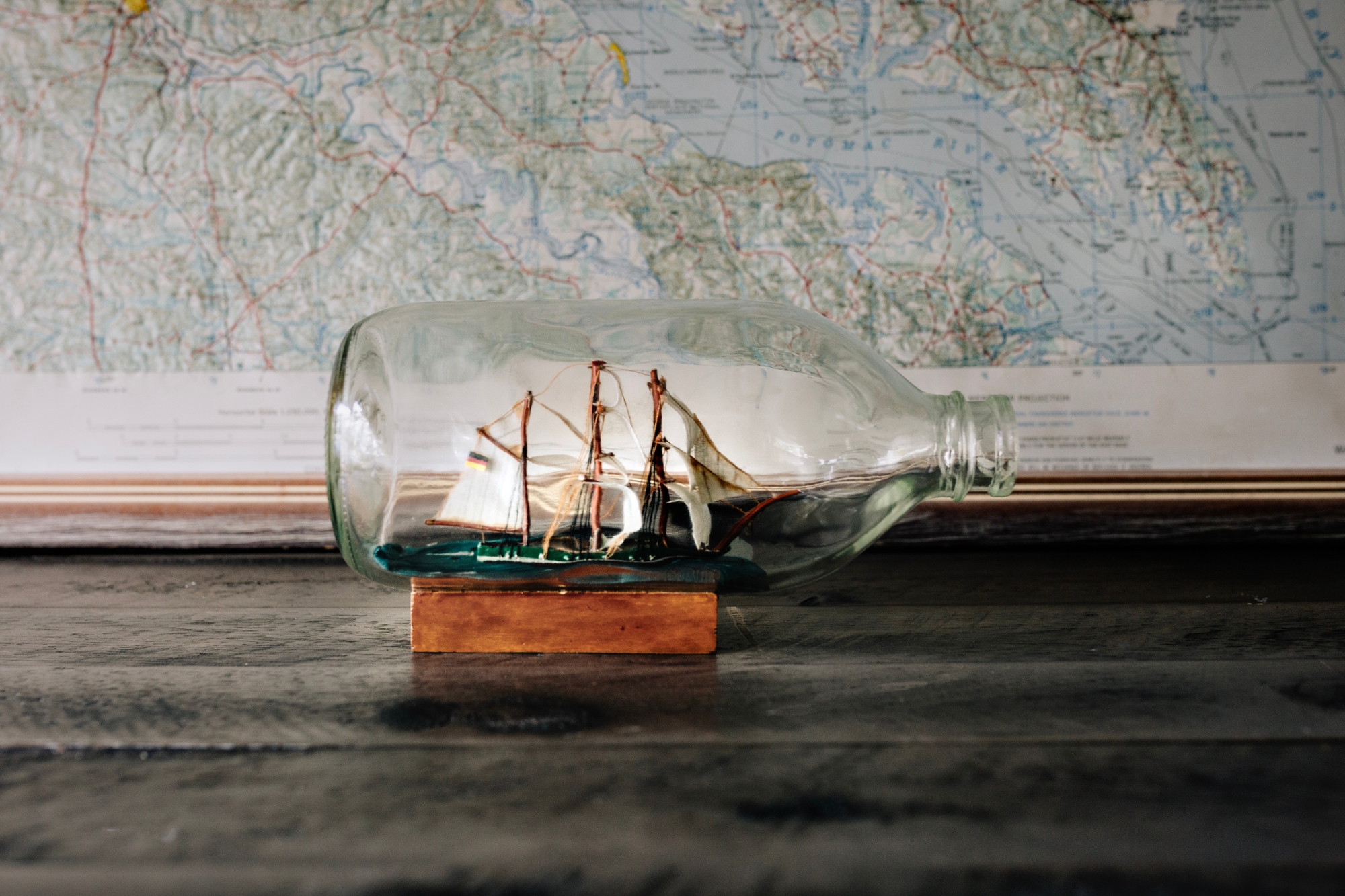 Boat in glass keep bottle displayed on a wooden stand.