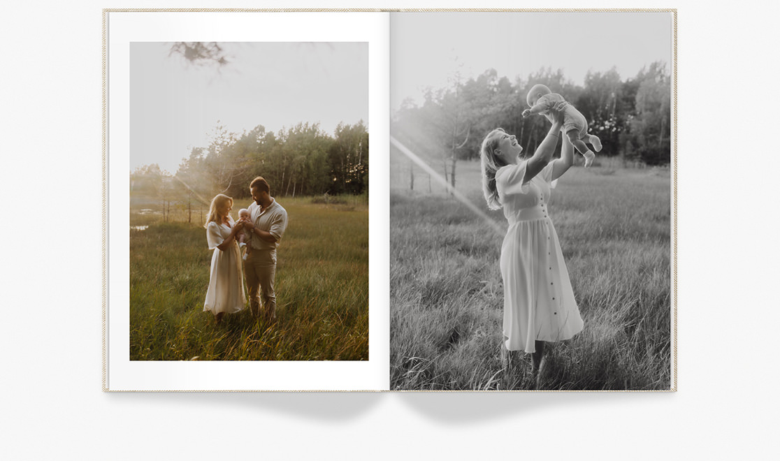 Open Portrait Premium Photo Book of family holding a baby on grassy field.