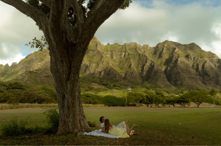Girl and boy on picnic rug under a treee