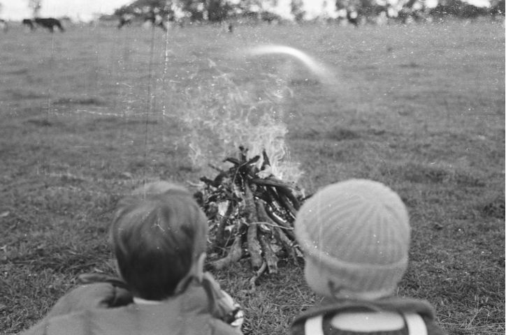 Two children sitting at a Bonfire in black and white