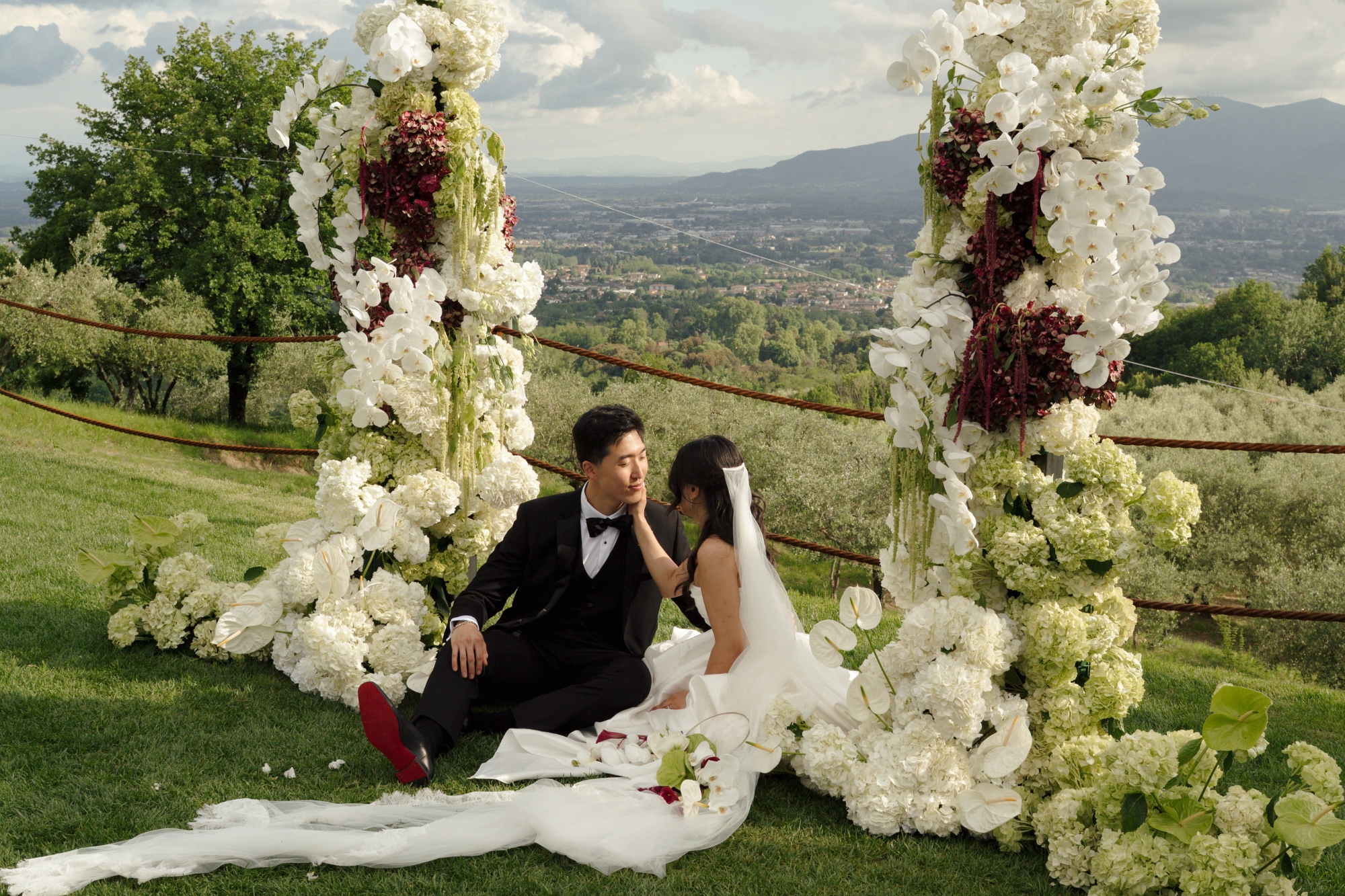 couple on wedding day sitting under floral arch