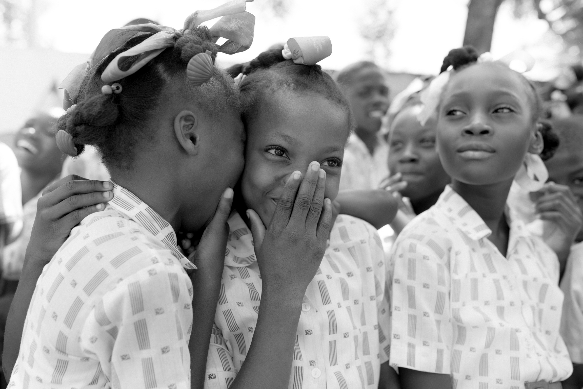 Girls whispering to eachother in black and white