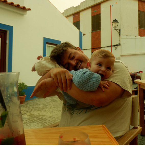 A man smiling and holding a baby