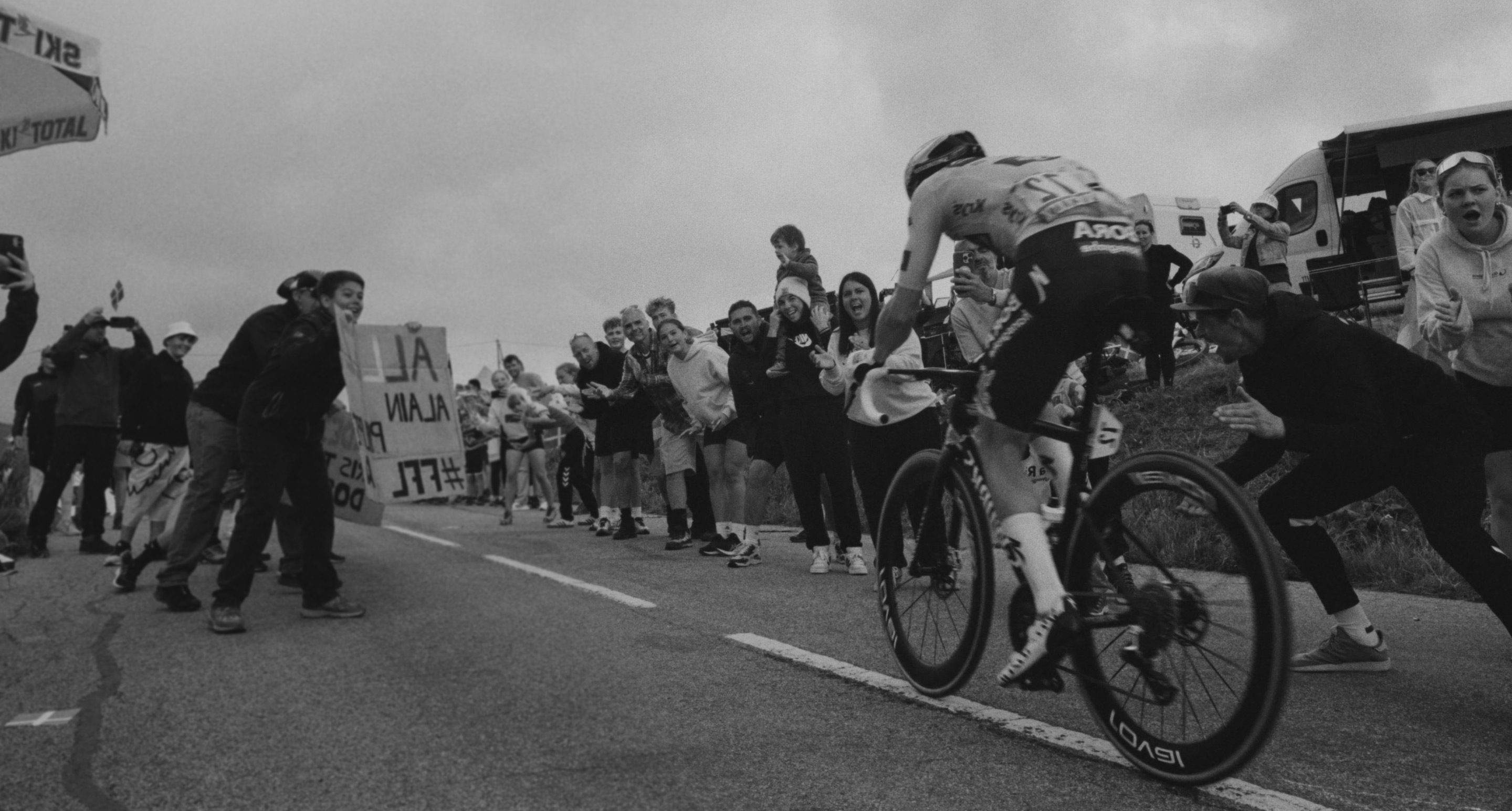 Un homme faisant du vélo, entouré de supporters.